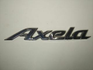 Фото запчасти эмблема багажника Mazda Axela контрактная запчасть Запчасть эмблема багажника Mazda Axela